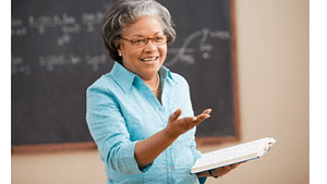 A picture of an older black women talking to a class in front of a chalk board