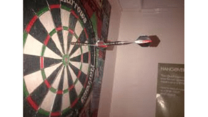 a picture of someone Aiming pass the dart board